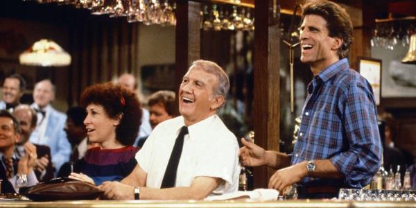 Sam, Coach, Carla, and others smiling at a bar in Cheers season 1